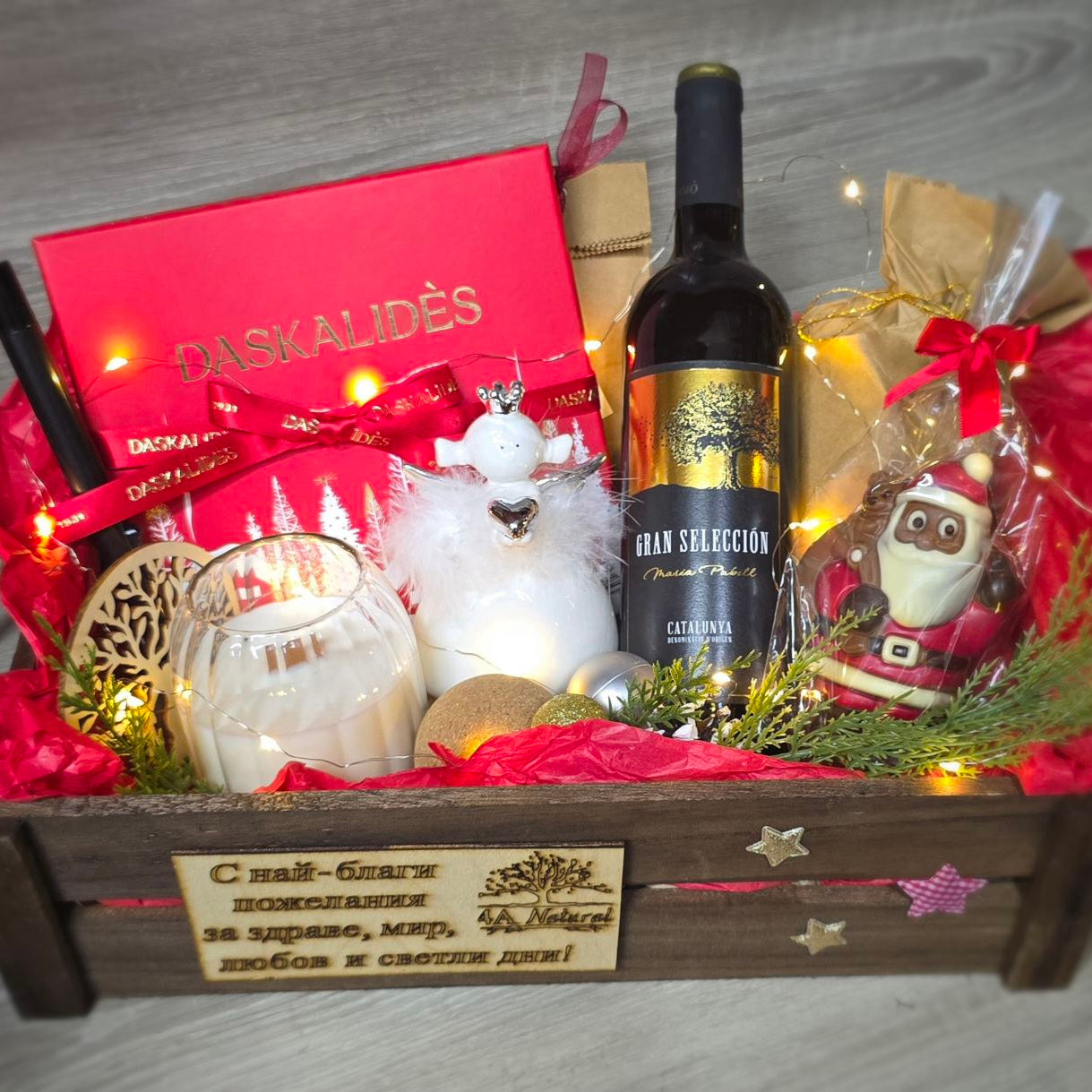 Gift basket with chocolate Daskalidès, wine, candles, and decorative items on a wooden surface