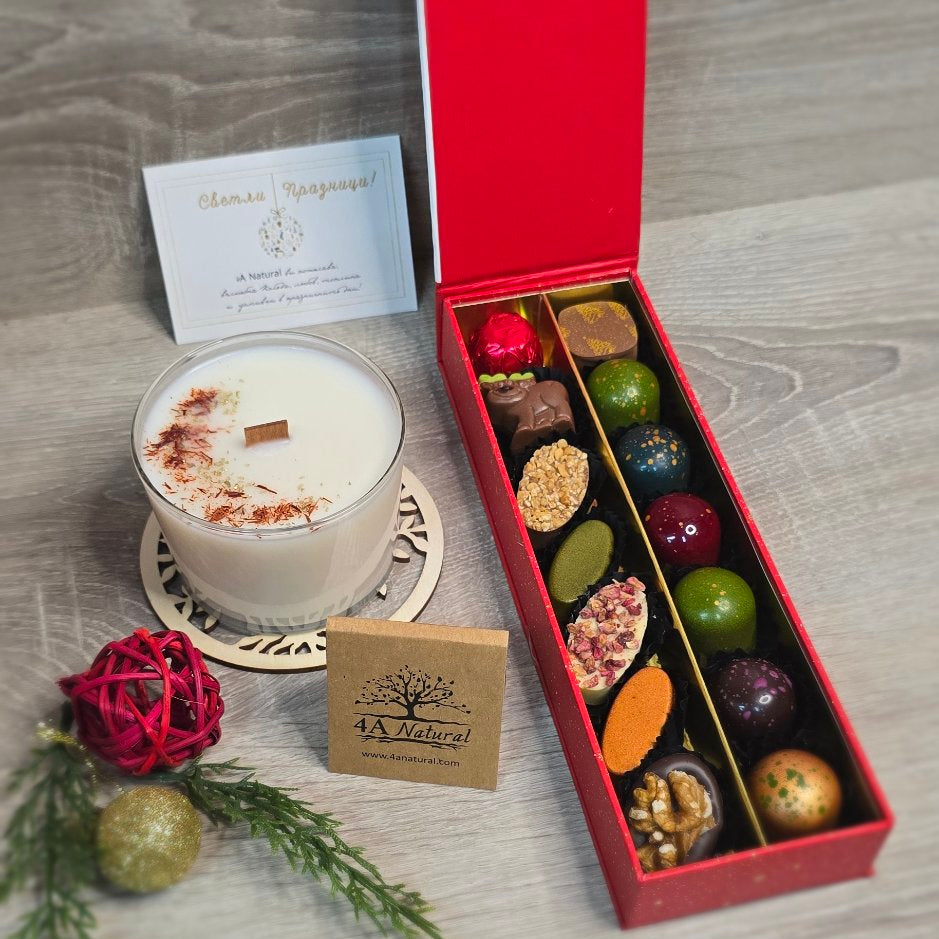 Candle with decorative elements and a box of chocolates on a wooden surface